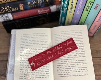Könnte beinhalten: Ein rotes Lesezeichen mit einem weißen Quasten, mit dem Text "Ich war in der Mitte, bevor ich wusste, dass ich angefangen hatte."