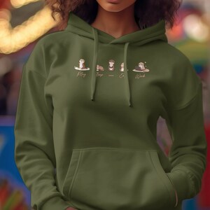 Pode incluir: Uma camisola de capuz verde com um gr&aacute;fico de quatro lontras de desenho animado. As lontras s&atilde;o etiquetadas como "Play", "Sleep", "Eat" e "Work".
