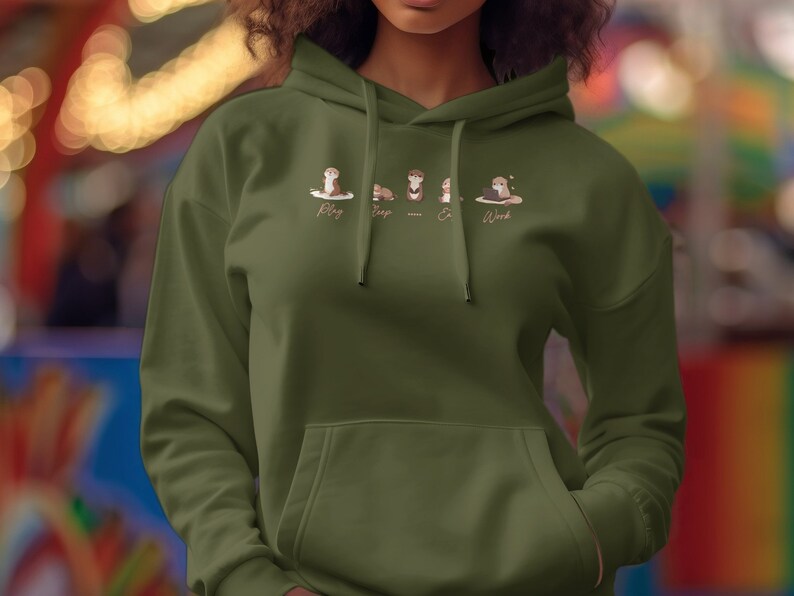 Pode incluir: Uma camisola de capuz verde com um gr&aacute;fico de quatro lontras de desenho animado. As lontras s&atilde;o etiquetadas como "Play", "Sleep", "Eat" e "Work".