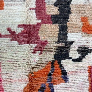 Puede incluir: Primer plano de una alfombra colorida con un patr&oacute;n geom&eacute;trico. La alfombra est&aacute; hecha de lana y tiene una superficie suave y texturizada. Los colores de la alfombra incluyen rojo, naranja, negro y blanco.