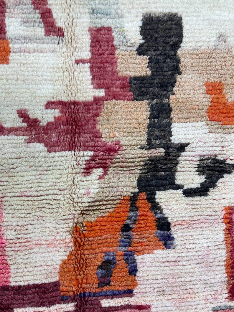 Puede incluir: Primer plano de una alfombra colorida con un patr&oacute;n geom&eacute;trico. La alfombra est&aacute; hecha de lana y tiene una superficie suave y texturizada. Los colores de la alfombra incluyen rojo, naranja, negro y blanco.