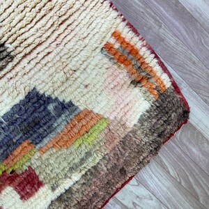 Puede incluir: Una alfombra colorida tejida a mano con un patr&oacute;n geom&eacute;trico en tonos de rojo, naranja, amarillo, verde, azul y marr&oacute;n. La alfombra tiene una textura gruesa y esponjosa y est&aacute; hecha de lana.