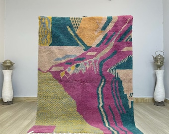 May include: A colorful abstract rug with pink, green, yellow, and beige tones. The rug has a modern, geometric design.
