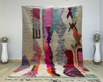 May include: A colorful Moroccan rug with abstract geometric patterns in shades of pink, red, green, blue, and orange on a cream background.