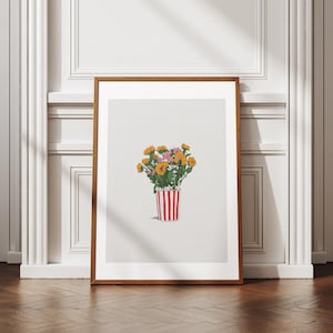Op de afbeelding: Een ingelijste kunstdruk met een boeket gele en roze bloemen in een rood-wit gestreepte container. Het kunstwerk staat tegen een witte achtergrond en is ingelijst in een bruine houten lijst. De print wordt op een houten vloer getoond.