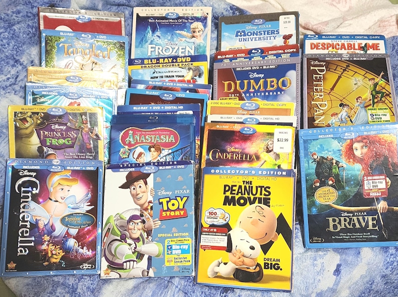 Puede incluir: Una colecci&oacute;n de estuches de Blu-ray y DVD con pel&iacute;culas de animaci&oacute;n populares, incluyendo Cenicienta de Disney, La Princesa y la Rana, Frozen, Toy Story y Brave de Pixar. Los estuches est&aacute;n dispuestos en una cuadr&iacute;cula sobre una superficie azul.