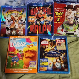 Puede incluir: Una colecci&oacute;n de cinco estuches de DVD Blu-ray con pel&iacute;culas de animaci&oacute;n populares. Los estuches son azules y presentan ilustraciones coloridas de los personajes de las pel&iacute;culas. Los t&iacute;tulos incluyen "Beverly Hills Chihuahua 2", "Rompe Ralph", "Toy Story 2", "El Lorax del Dr. Seuss" y "La Bella y la Bestia".