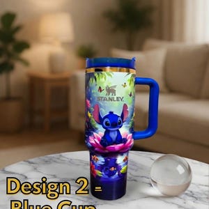 May include: Blue Stanley tumbler with a wraparound design featuring a cartoon character. The tumbler has a blue handle and lid, with the text "Craftycustom" at the top. The words "Design 2 - Blue Cup" are at the bottom.