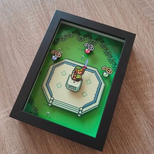 Könnte beinhalten: Gerahmte Pixelkunst mit einer Szene aus einem Videospiel. Das Kunstwerk zeigt eine Figur mit einem Schwert auf einer Plattform, umgeben von einer grünen Landschaft. Der Rahmen ist schwarz.