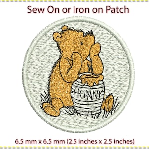 May include: A round, white iron-on or sew-on patch featuring a cartoon Winnie the Pooh holding a honey pot. The patch is 6.5 cm in diameter.