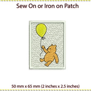 May include: Embroidered patch featuring a cartoon bear holding a yellow balloon. The patch is rectangular with a light gray background and a white border. The text "Sew On or Iron on Patch" is at the top. The patch measures 2 inches x 2.5 inches.