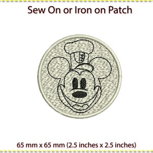May include: A white iron-on or sew-on patch featuring a black and white outline of Mickey Mouse's face. The patch is 6.5 cm by 6.5 cm.