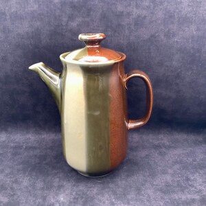 May include: A ceramic coffee pot featuring a vertical color-blocked design with alternating bands of olive green, light beige, and deep reddish-brown. The pot includes a matching lid with a knob handle, a curved spout, and a sturdy side handle.