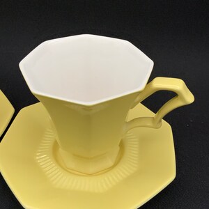 K&ouml;nnte beinhalten: Ein gelbes achteckiges Teetassen- und Untertassen-Set. Die Tasse hat ein wei&szlig;es Inneres und einen leicht ausgestellten Rand. Die Untertasse hat einen gewellten Rand.