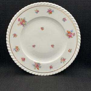 May include: White ceramic plate with a gold rim and a floral pattern. The flowers are pink, red, yellow, and blue.