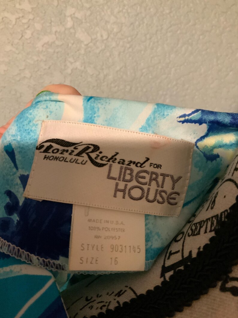Puede incluir: Una prenda con un patr&oacute;n floral abstracto en azul y blanco y una etiqueta de tela blanca que dice Lori Richard Honolulu for Liberty House. Una etiqueta m&aacute;s peque&ntilde;a debajo indica Made in U.S.A., 100% poli&eacute;ster, RN 20957, estilo 9031145, talla 16.