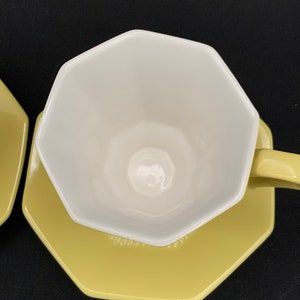 K&ouml;nnte beinhalten: Eine gelbe achteckige Untertasse mit einer wei&szlig;en achteckigen Teetasse darauf. Tasse und Untertasse sind beide aus Keramik.