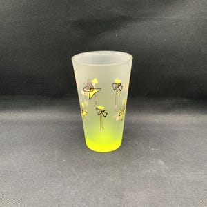May include: A frosted glass tumbler featuring a vibrant neon yellow base that fades into a translucent finish. The exterior is decorated with a repeating pattern of black line-drawn geometric shapes, yellow accents, and small pink rectangular details.