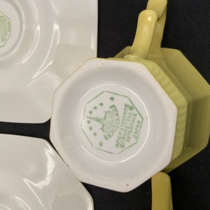 K&ouml;nnte beinhalten: Ein Set aus vier gelben Teetassen und Untertassen. Die Tassen und Untertassen haben eine achteckige Form. Auf der Unterseite der Tassen und Untertassen befindet sich ein gr&uuml;nes Logo mit der Aufschrift "INDEPENDENT IRONSTONE INTERSPACE JAPAN".