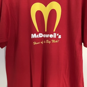 May include: Red t-shirt with a yellow McDonald's-style logo and the text "McDowell's Home of the Big Mick!"