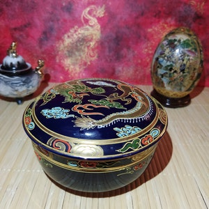 May include: A blue and gold ceramic trinket box with a dragon design. The box has a lid and is decorated with intricate details.