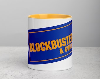 May include: White ceramic mug with a yellow rim. The mug has a blue and yellow graphic that says "Blockbuster & Chill".