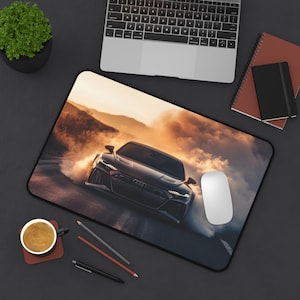 May include: A black Audi sports car driving on a road with smoke coming from the tires. The car is in focus and the background is blurred. The car is driving on a road with a sunset in the background.