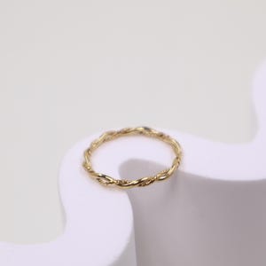 May include: A gold twisted band ring. The ring is simple and delicate.