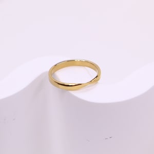 May include: A simple gold band ring with a twisted design.