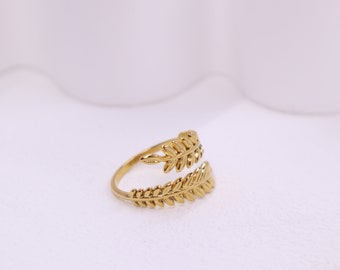 May include: A gold ring with a leaf design. The ring is open on one side and has a delicate, intricate design.