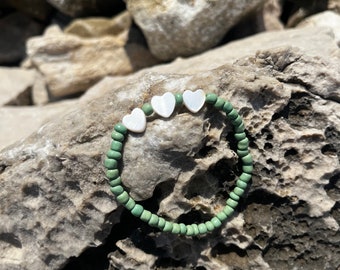 May include: A green beaded bracelet with four white heart-shaped charms.