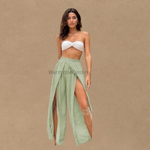 Puede incluir: Un top tipo tubo blanco sin tirantes con un detalle retorcido en el centro, combinado con pantalones anchos de color verde salvia con aberturas laterales altas que se extienden desde la cintura hasta el dobladillo. El texto WardrobeDestiny es visible.