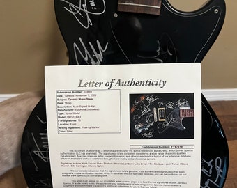 Keith Urban y otros firman guitarras.