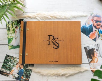 May include: A wooden photo album with a black spine and brass accents. The cover is engraved with the initials "RS" and the text "Richard & Sanchez" and the date "12.11.2022".