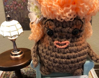 Snarky Spud Fawn Dior est une nouvelle version crochetée à la main de la pomme de terre positive. C'est un cadeau idéal pour les amis qui aiment l'humour.