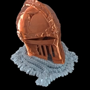Peut inclure: Un casque de couleur cuivre avec un col de cotte de mailles. Le casque présente des détails complexes et une visière.