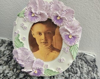 Marco de fotos ovalado de cerámica vintage con ramo floral morado, blanco y verde.