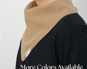 Puede incluir: Un pañuelo de algodón de color marrón claro con un logotipo blanco. El pañuelo está atado alrededor del cuello de una persona que lleva una camisa negra. Más colores disponibles.