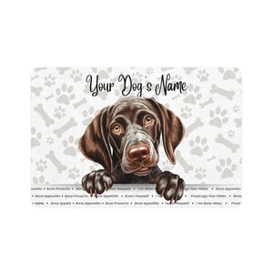 May include: A rectangular pet mat featuring a brown dog illustration with the text "Your Dog's Name". The background has a pattern of paw prints and bones. The dog's eyes are yellow.