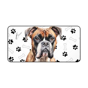May include: A rectangular dog mat featuring a Boxer dog portrait. The mat has a white background with a repeating pattern of black paw prints and bone shapes. The word "Boxer" is written in cursive.