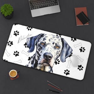 May include: White rectangular desk mat featuring a Dalmatian dog portrait with black spots and brown eyes. The mat has a paw print and bone pattern, with the word "Dalmatian" in script. A computer mouse rests on the mat.
