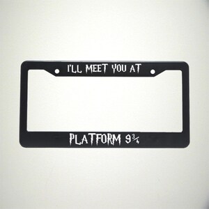 May include: Black license plate frame with white text that reads "I'll meet you at Platform 9 3/4".