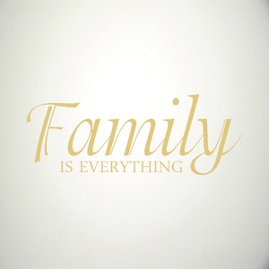 Może przedstawiać: Złota naklejka ścienna z winylu z tekstem "Family is Everything" w ozdobnym, pisanym stylu.