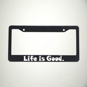 May include: Black plastic license plate frame with the text "Life is Good." in white lettering.