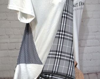 May include: A grey and black plaid pet carrier with a zipped pocket and a white fleece lining. The carrier has a long strap for carrying over the shoulder. The text "Pocket Dog" and "Pet Boutique" is visible on the carrier.