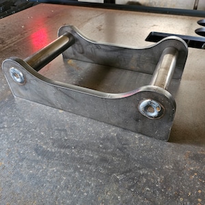 Könnte beinhalten: Eine Metallhalterung mit zwei runden Stäben, wahrscheinlich zum Stützen oder Befestigen von etwas.