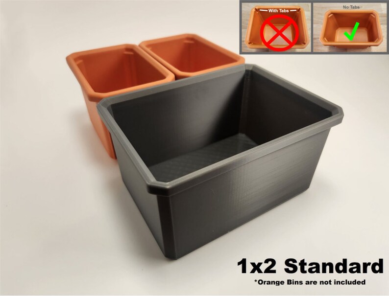 May include: A grey plastic storage bin with a 1x2 standard label. The bin is empty, but two orange plastic bins are visible in the background. The orange bins are not included.