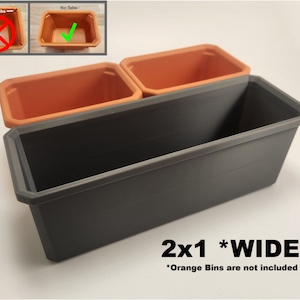May include: A wide, grey plastic planter with two orange plastic bins inside. The planter is labelled "2x1 *WIDE*" and "Orange Bins are not included".