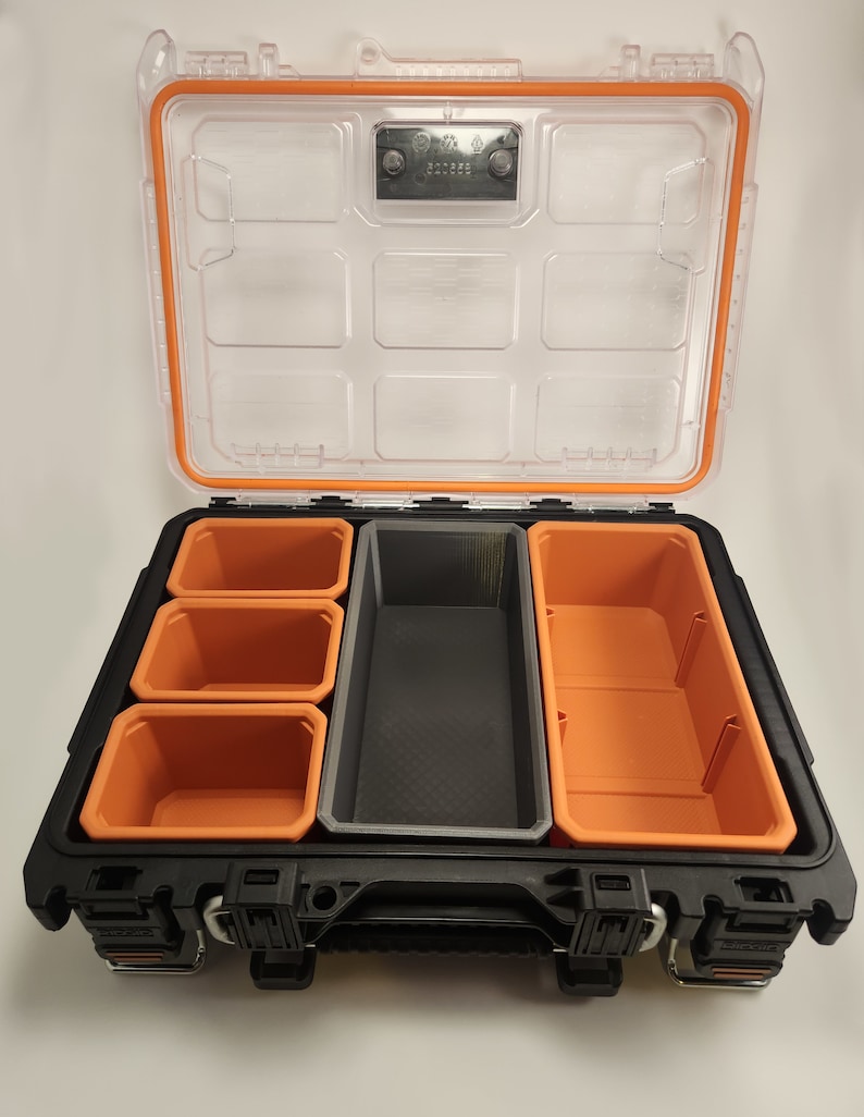 May include: A black and orange plastic tool box with a clear lid. The box has multiple compartments for organising small tools and parts.