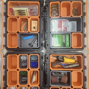 May include: An orange and black toolbox with multiple compartments filled with various hardware and tools, including screws, nails, drill bits, sanding discs, and a small power tool.
